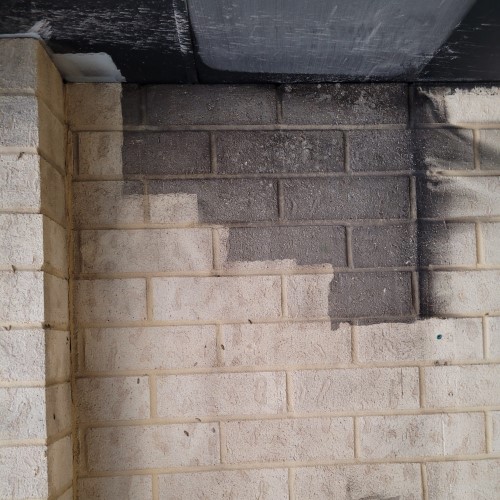 White painted brick wall with smoke damage partially laser cleaned, paint and surface preserved